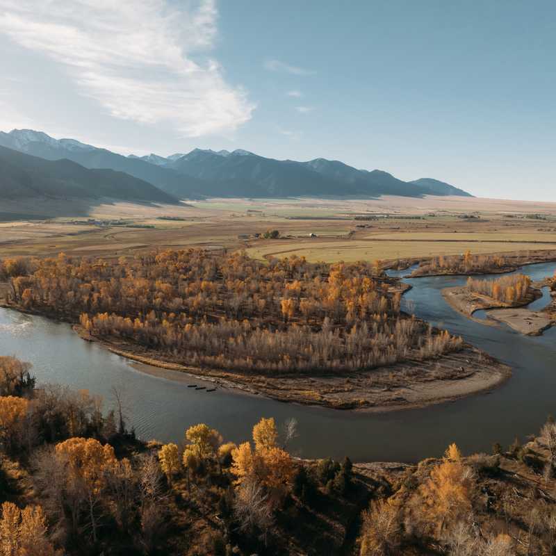 Aerial view of the Yellowstone River winding through Montana’s fall-colored landscape with surrounding mountains in the distance
