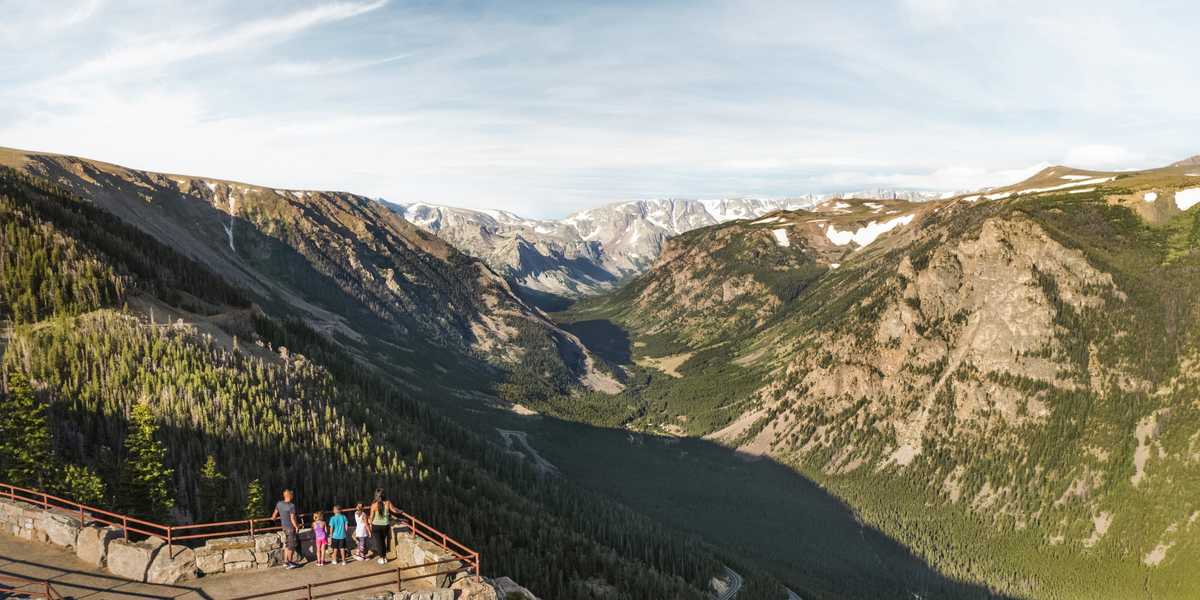 View from a scenic overlook in Montana looking over a mountain valley with forests, winding roads, and distant peaks