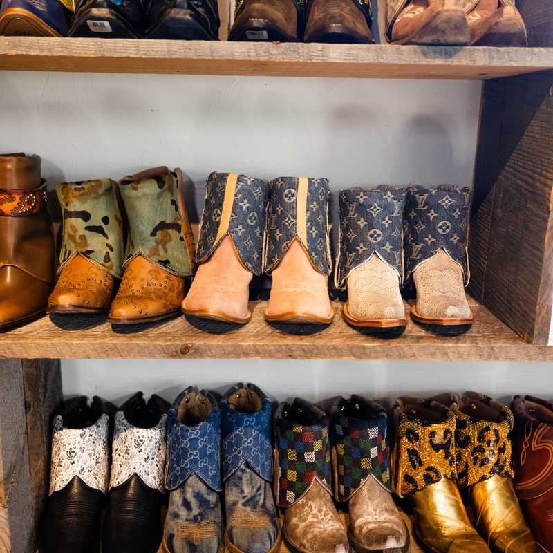 Rows of colorful cowboy boots displayed on shelves for sale in a Western-style shop