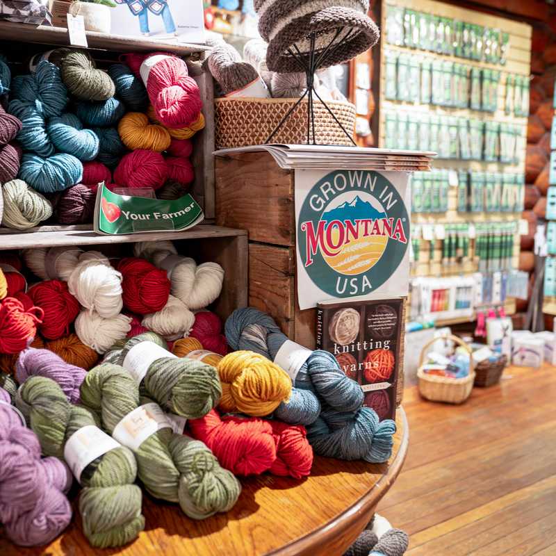 Montana-themed yarn shop display with stacked skeins of colorful yarn and a “Grown in Montana USA” sign