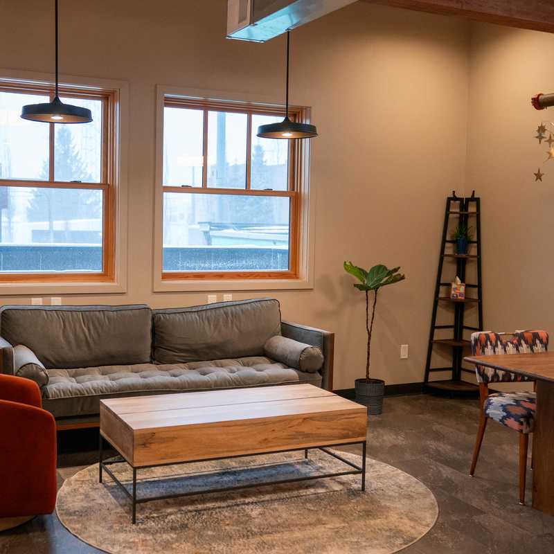 Modern living room with sofa and coffee table in a Montana cabin interior, plus dining table setup near large windows