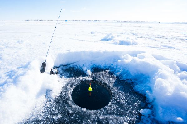 Angler pulls a line through the ice over a hole on a frozen lake in Montana