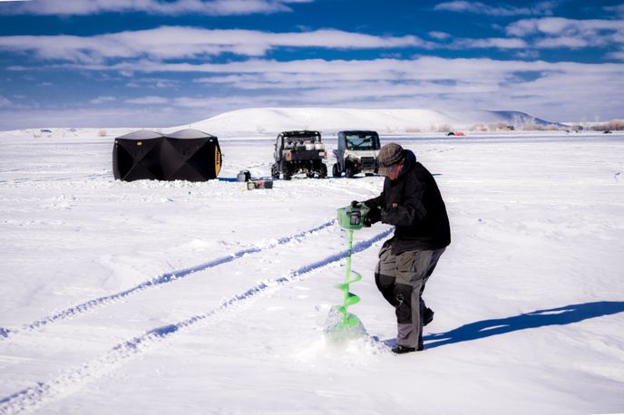 Fisherman drilling an ice fishing hole