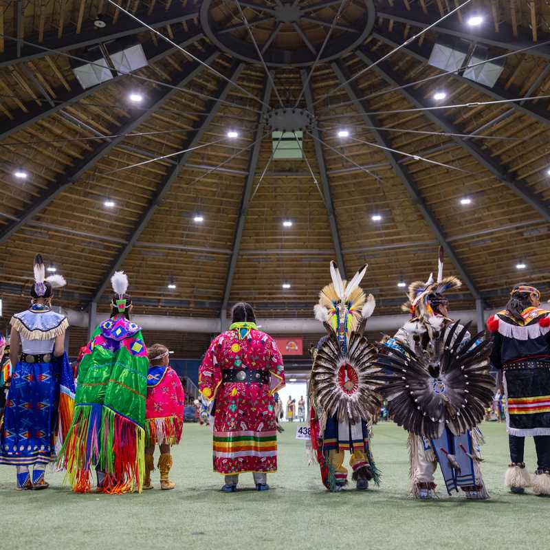 Colorful Indigenous dance regalia on display indoors during a powwow in Montana