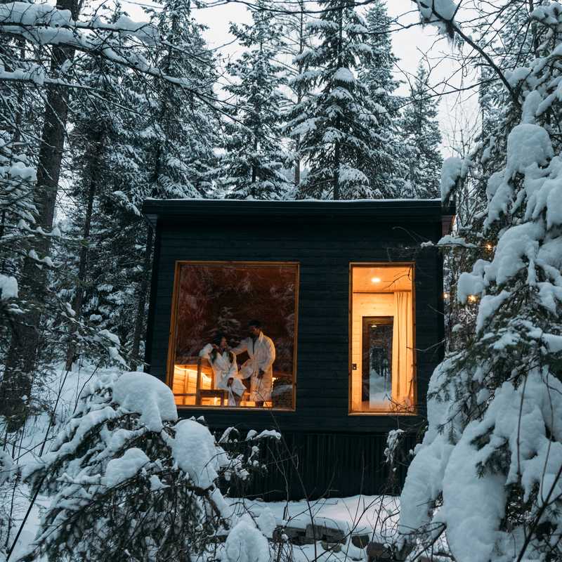 Cozy cabin at night in a snowy Montana forest with warm light glowing through the windows