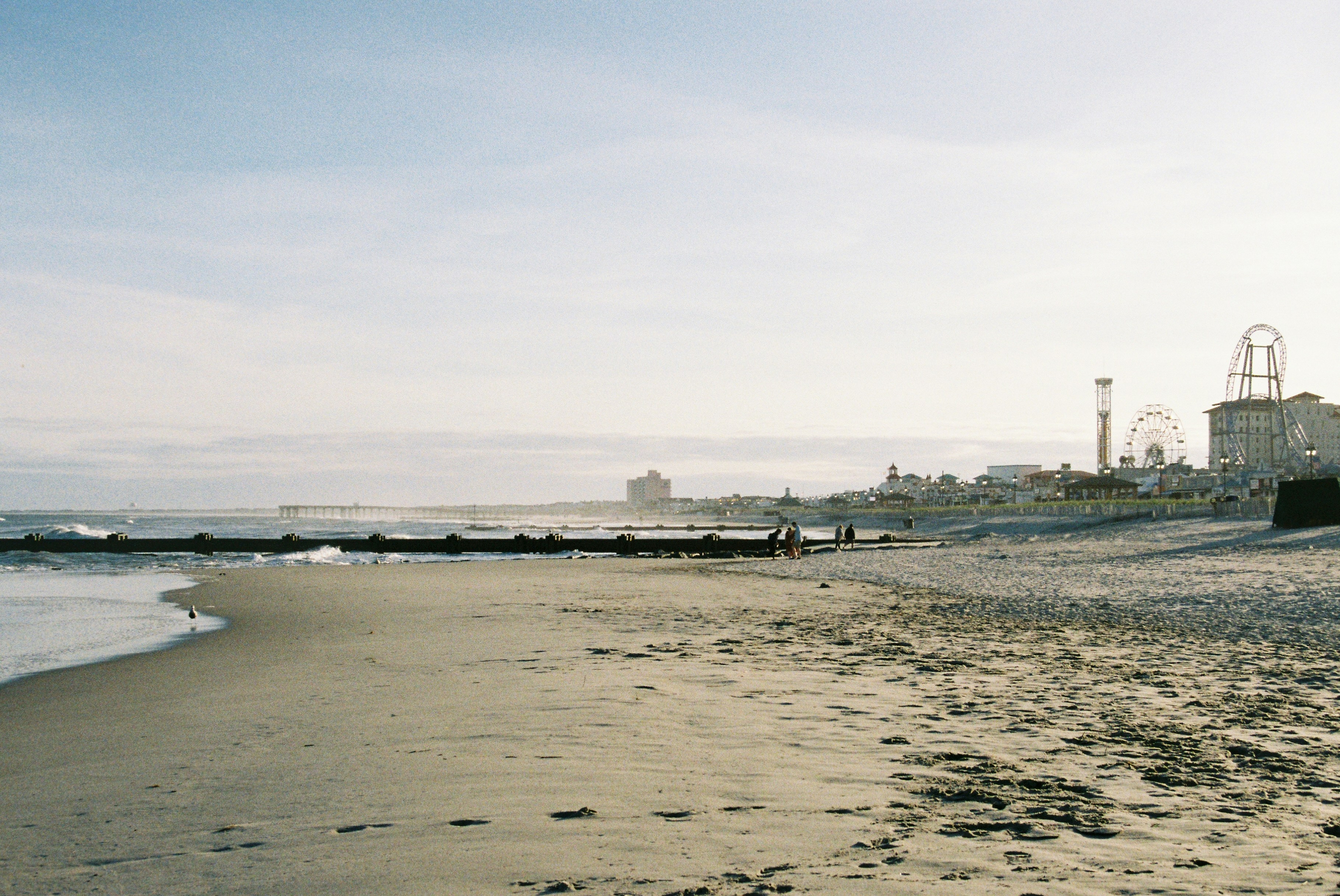 Ocean City's sandy beach with an amusement park featuring a Ferris wheel in the background.