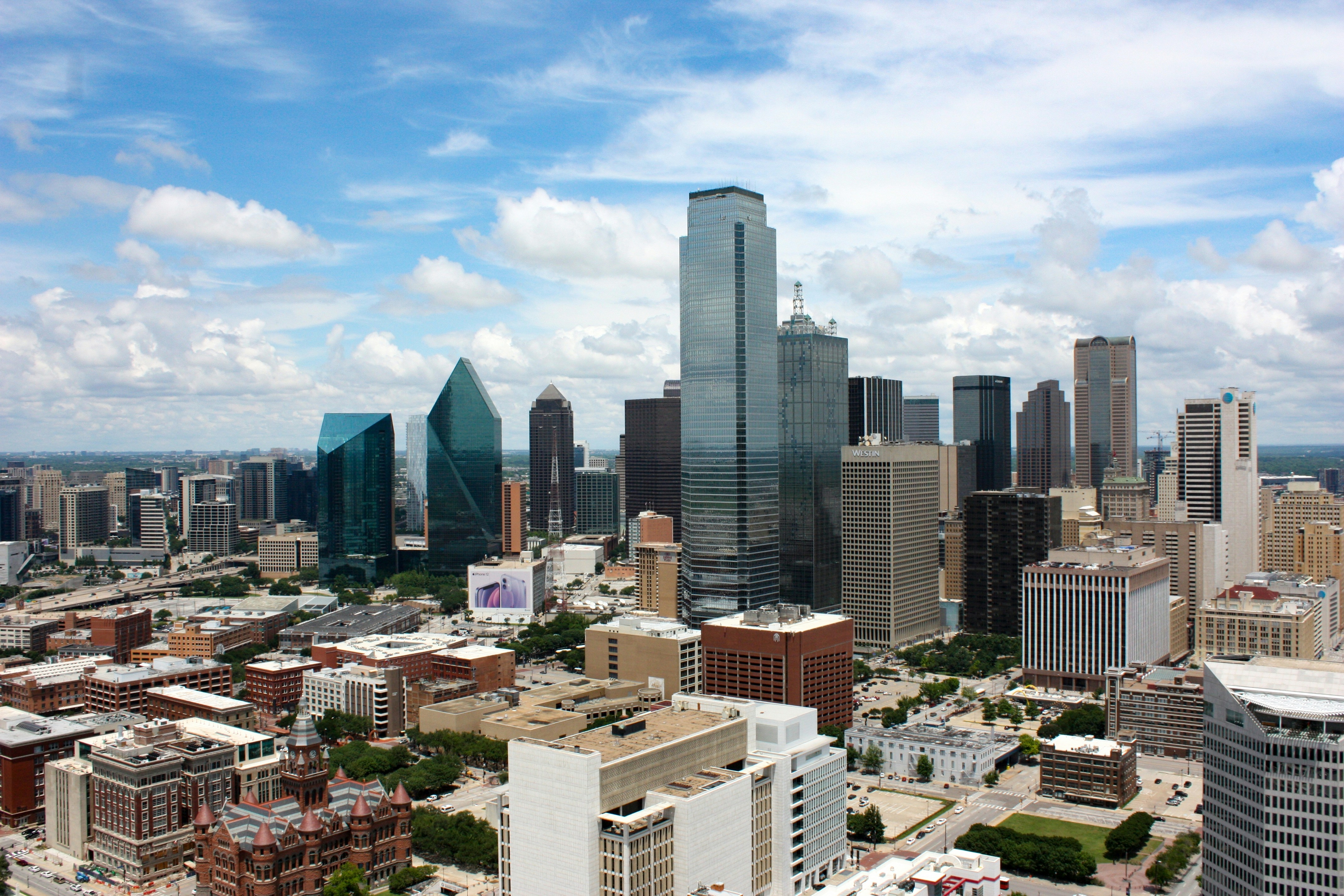 Aerial view of a city skyline with modern skyscrapers, under a partly cloudy sky.