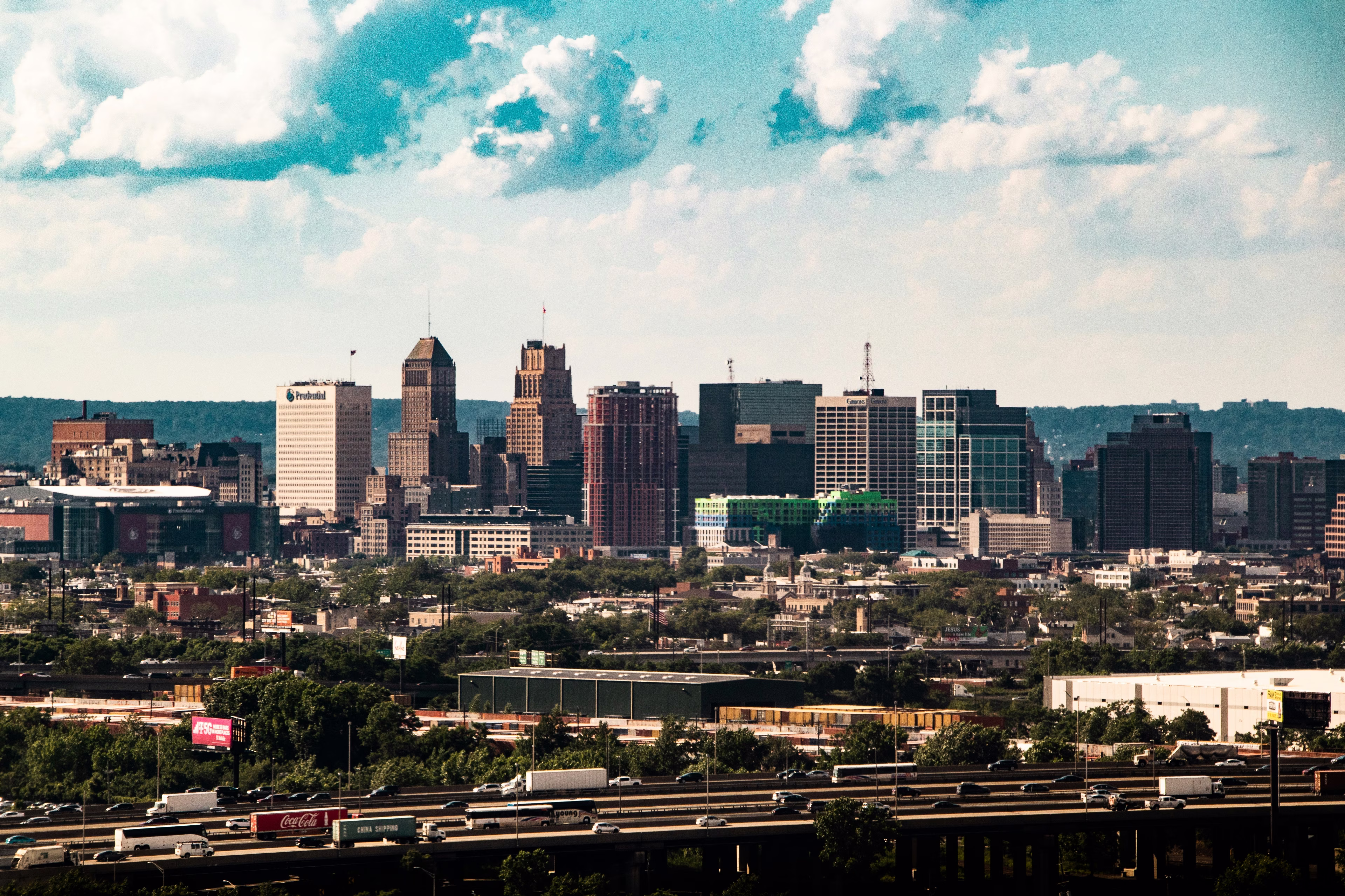 Buildings in downtown Newark, New Jersey, under a blue sky with highways full of cars and traffic.