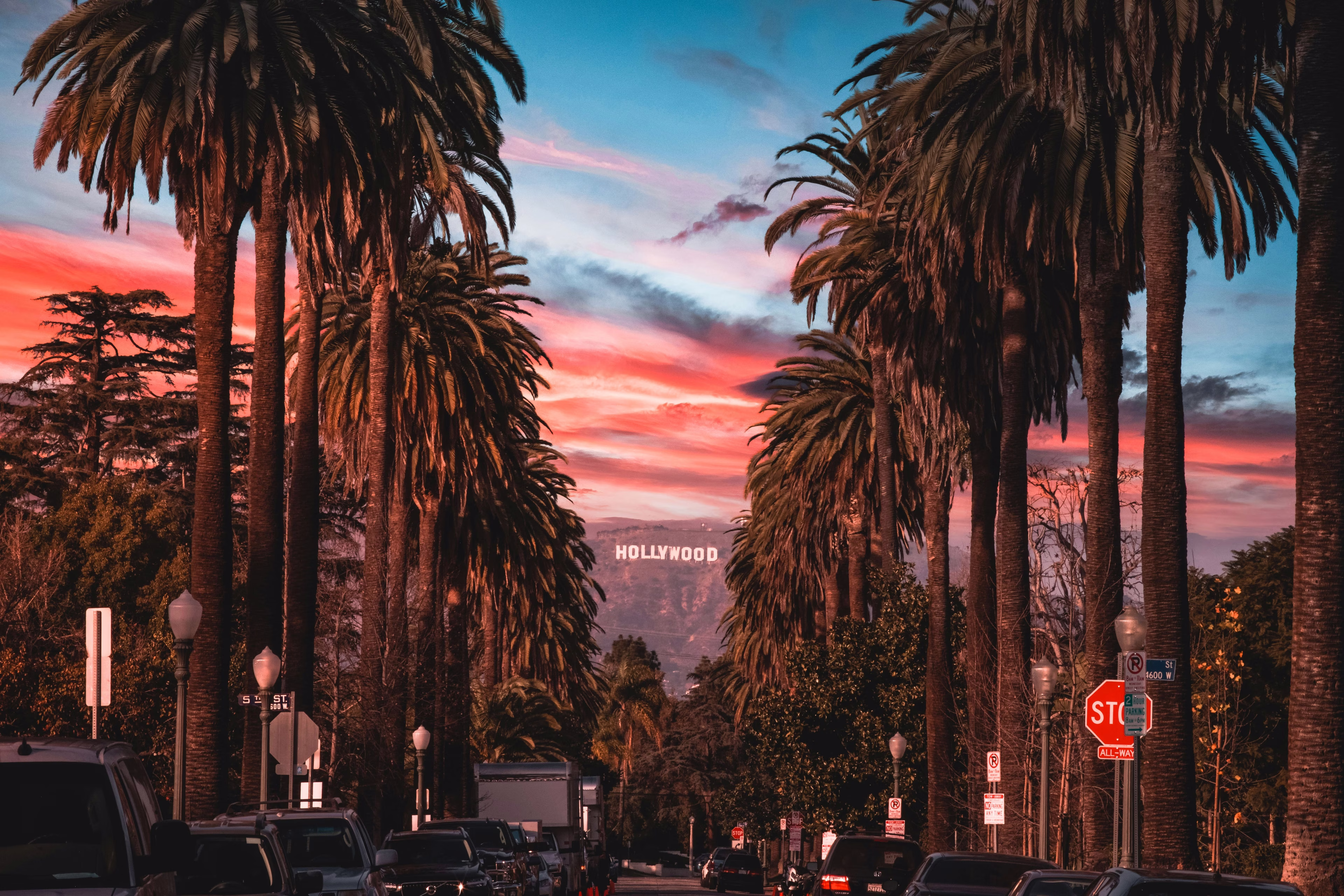 Hollywood sign view at sunset framed by palm trees in Los Angeles, California.