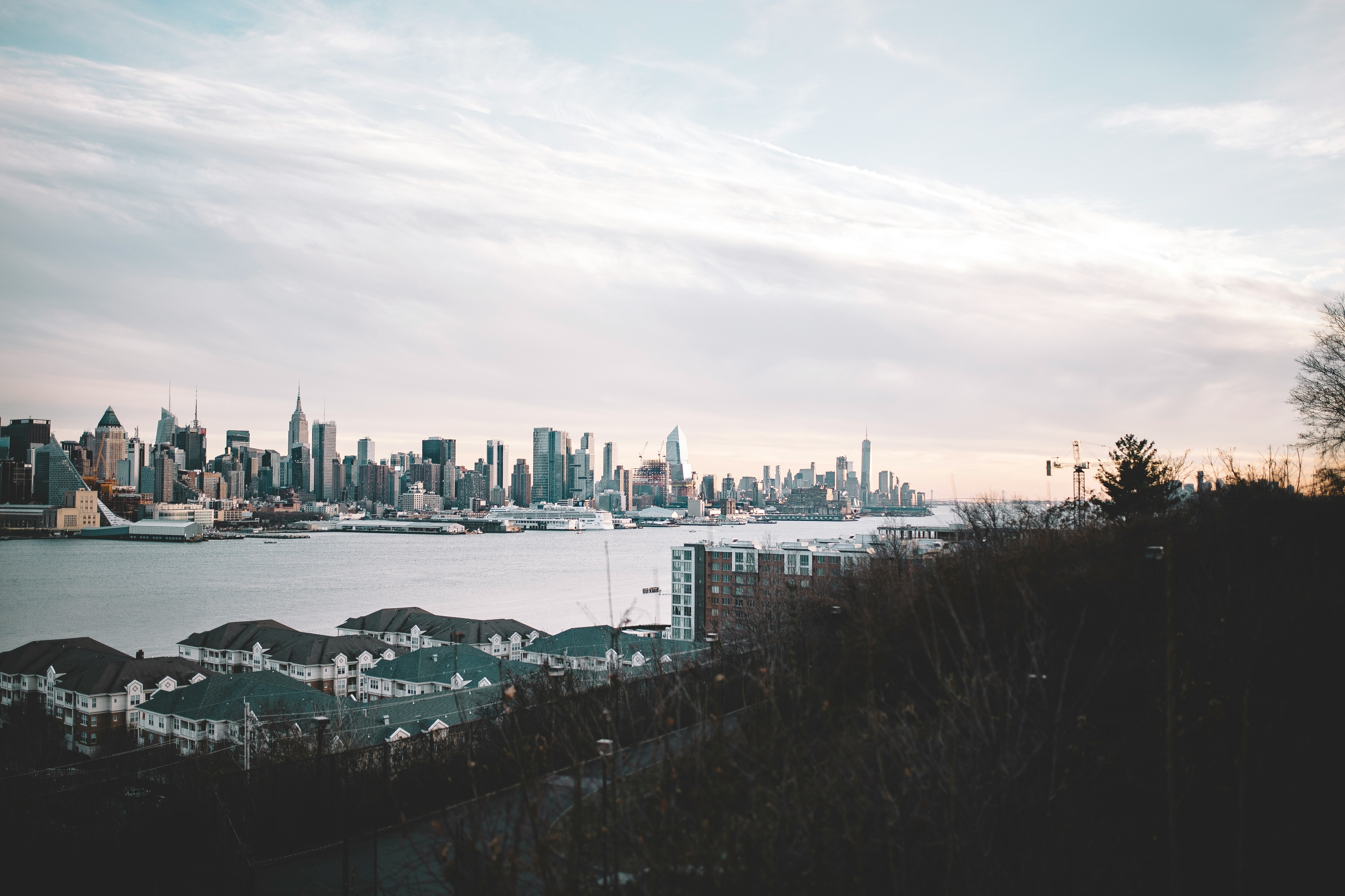 View of a row of houses in West New York, New Jersey, surrounded by trees with the New York City skyline in the background