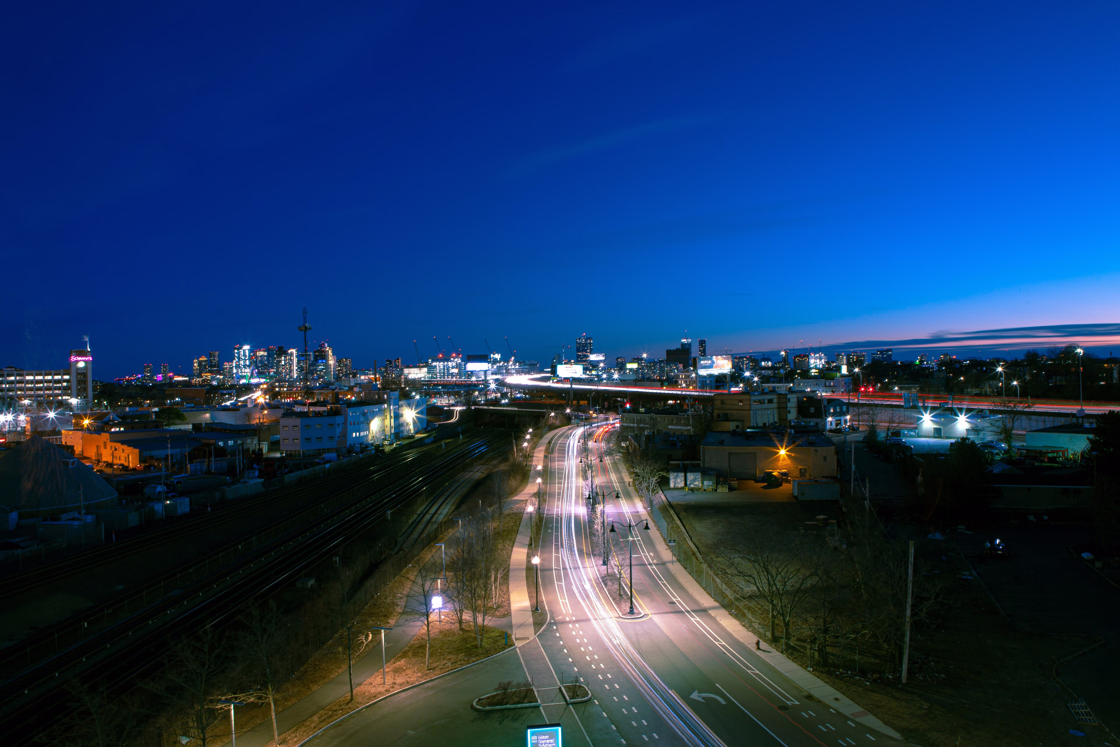 Somerville at dusk with illuminated roads and buildings under a deep blue sky.