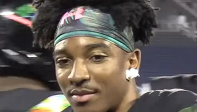 A person wearing a colorful headband and earrings, looking to the side, with a blurred background.