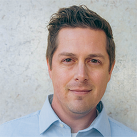 A headshot of a man with short brown hair wearing a light blue shirt looking directly at the camera.