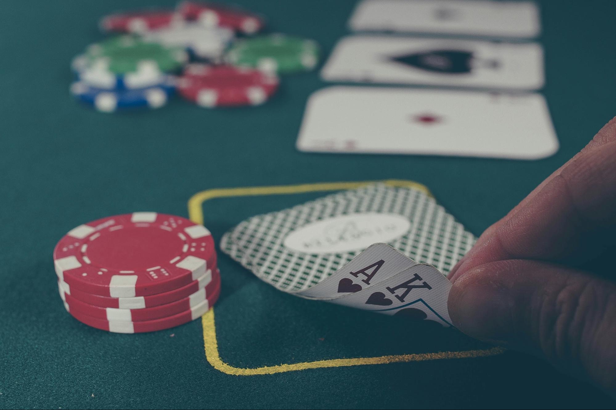 A poker player is revealing their hand next to a stack of chips while testing their poker bluff catcher strategy.
