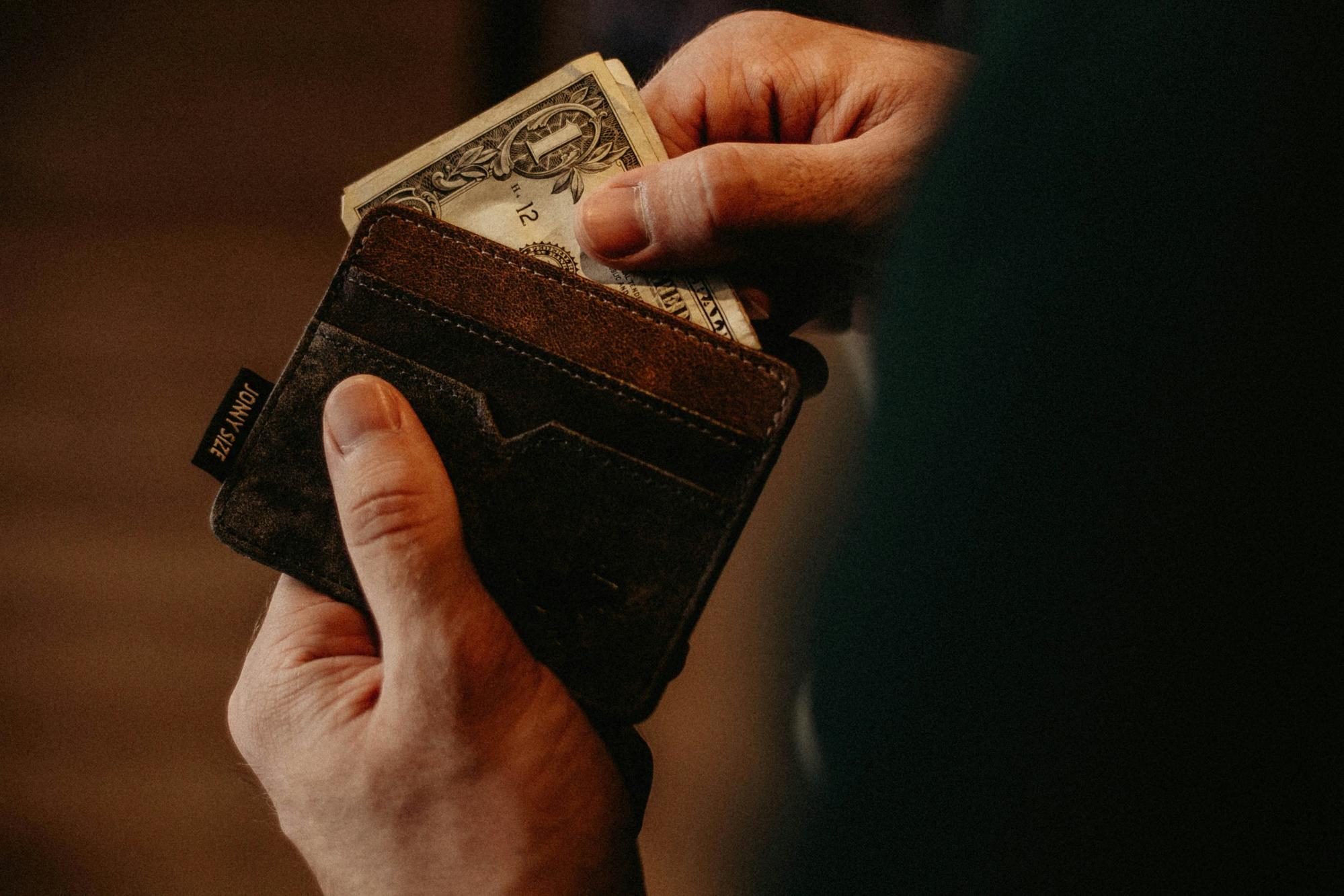 A person is following one of the best casino slot tips and removing a designated amount of cash from their wallet.