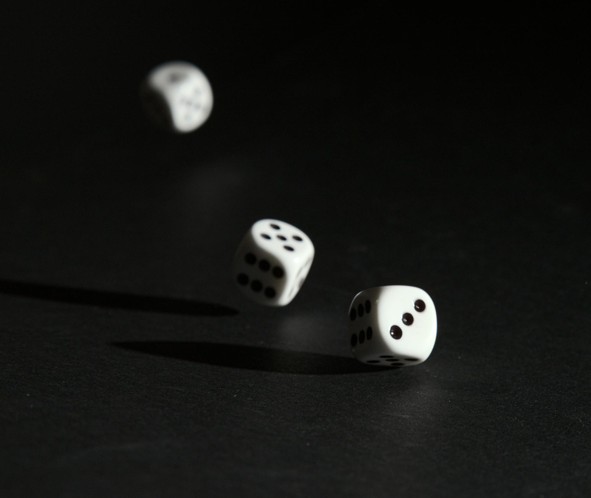 Dice rolling on a dark surface, to represent how the history of gaming in New Hampshire evolved from early gaming to video lottery technology