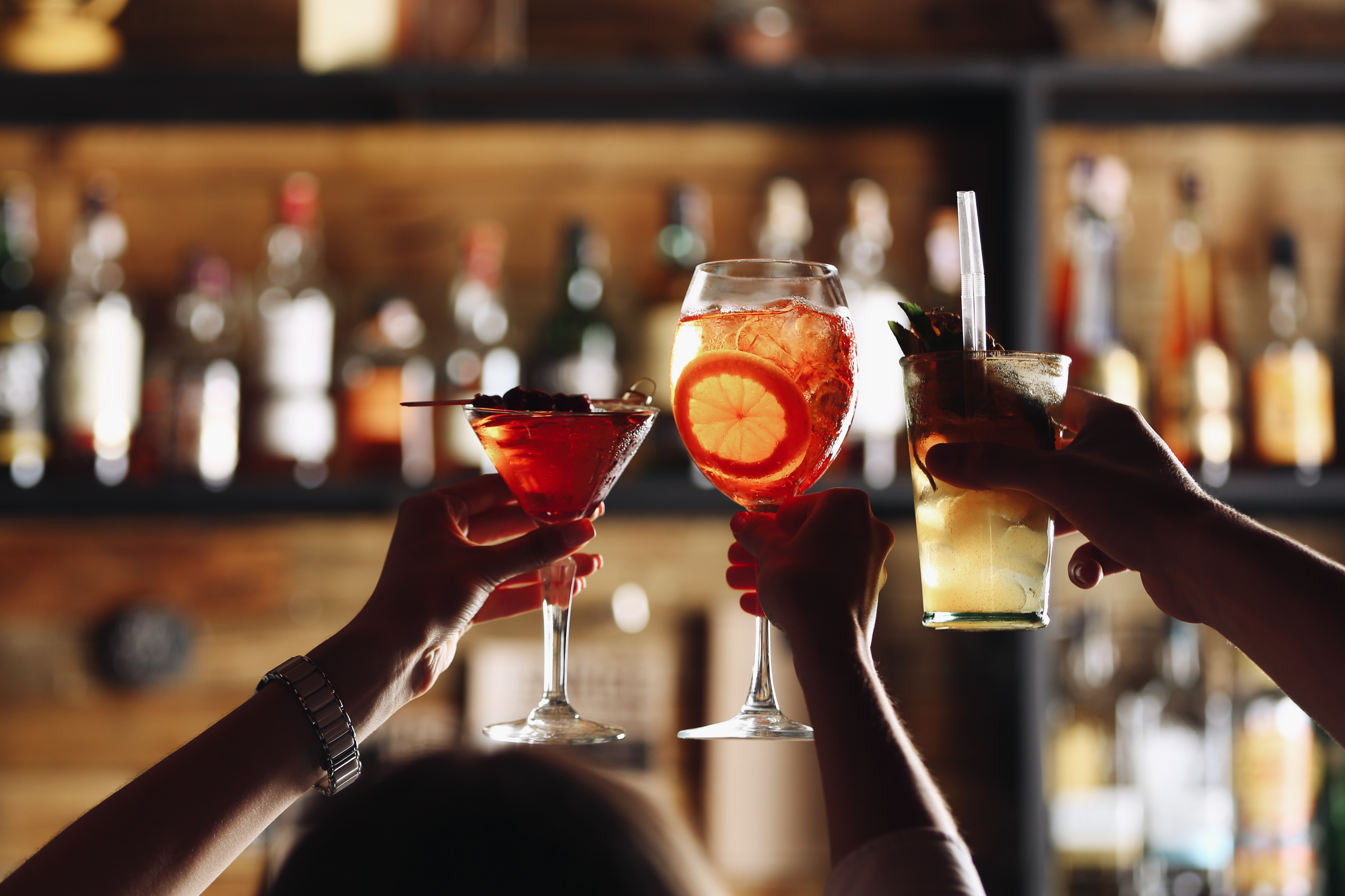 Three friends toast their cocktails to celebrate a fun gaming experience in Nashua