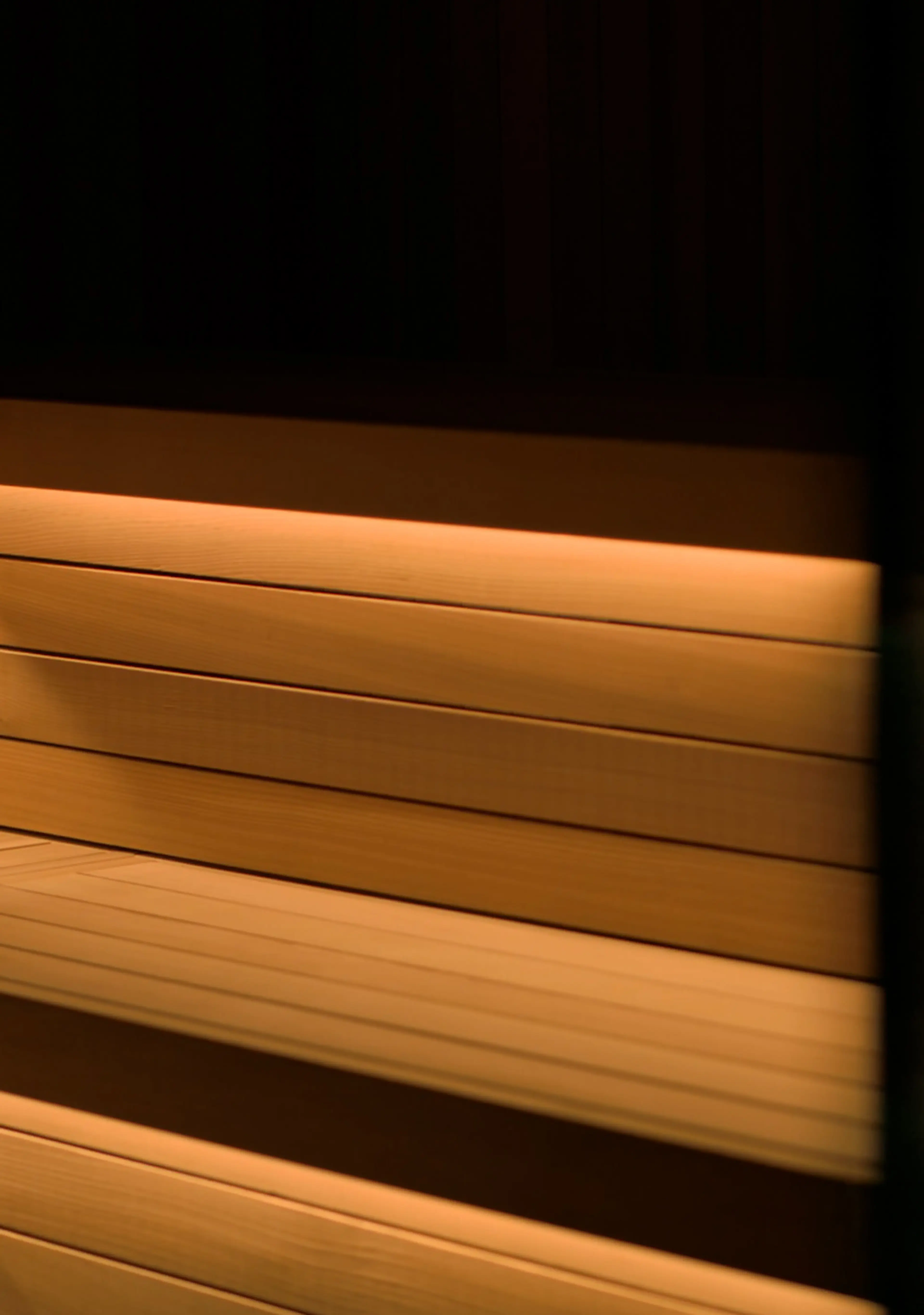 Wooden sauna benches with warm, soft lighting creating a cozy atmosphere.
