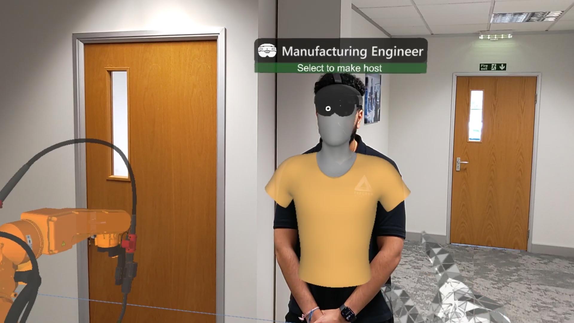 A Manufacturing Engineer wearing a HoloLens 2 Mixed Reality headset stands in an office space near a virtual robot arm