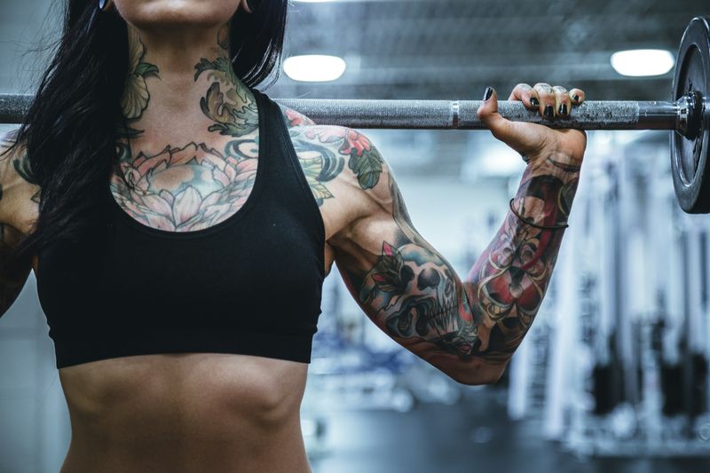 woman holding a barbell - Weightlifting Standards
