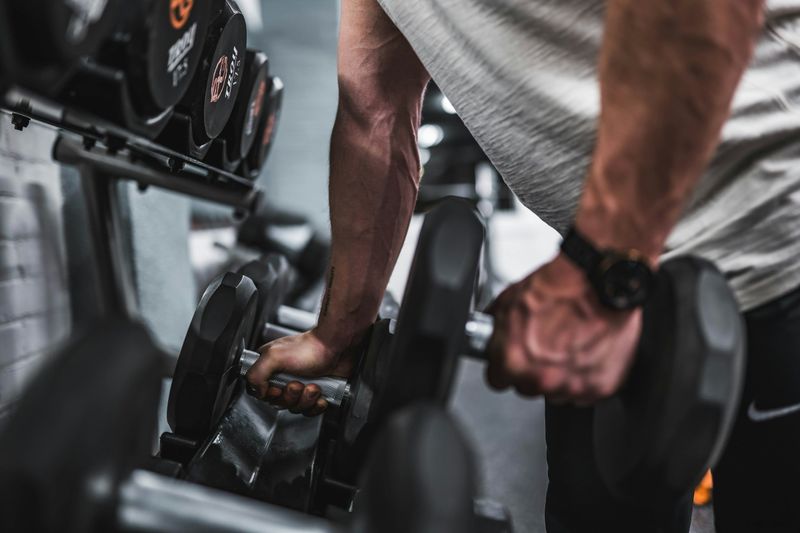 man holding dumbbells - Weightlifting Standards