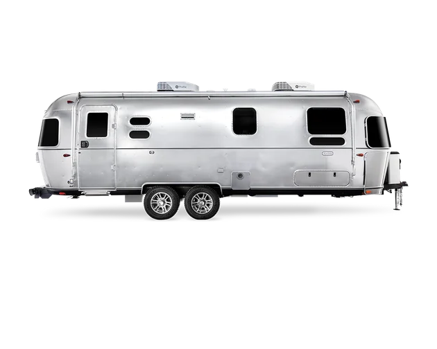 Silver Airstream travel trailer with dual axles, multiple windows, and a sleek, modern design.