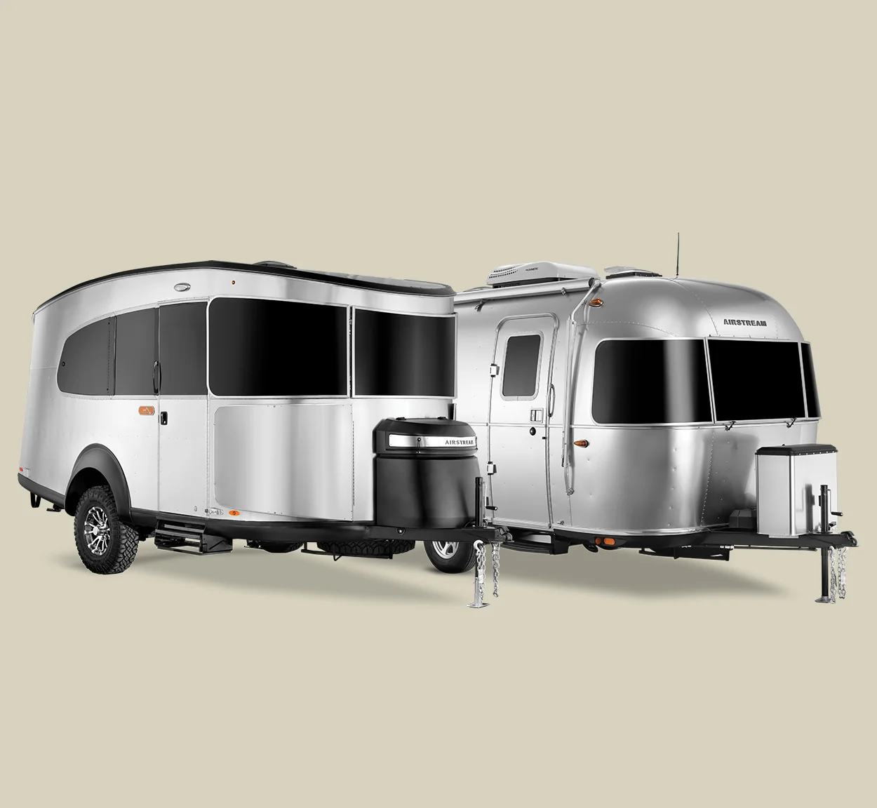 Two shiny, modern Airstream travel trailers side by side, featuring sleek aluminum exteriors and large windows against a neutral background.
