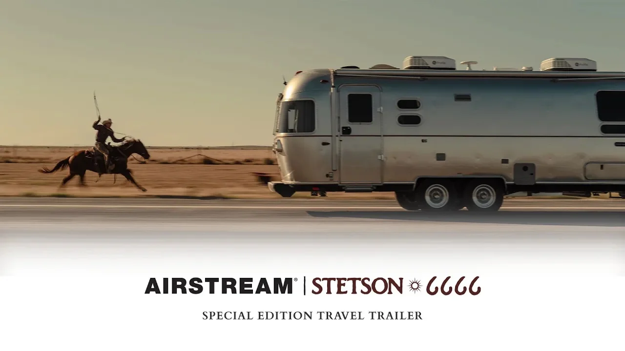 A cowboy on horseback gallops beside an Airstream trailer on a road with desert scenery, promoting a special edition travel trailer.