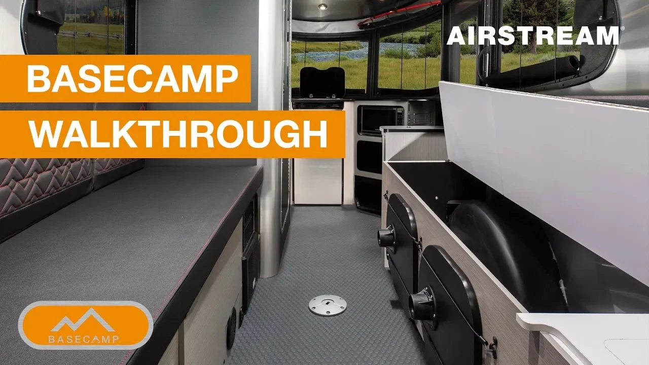 Interior view of an Airstream Basecamp trailer featuring seating, storage, and appliances, with text "Basecamp Walkthrough" in orange.