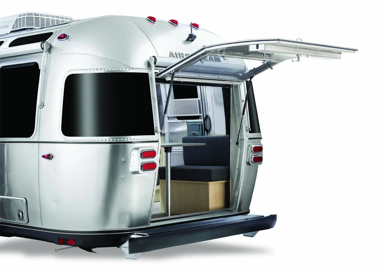 A silver Airstream trailer with an open rear hatch, revealing the interior seating area. The design features sleek curves and minimalistic style.