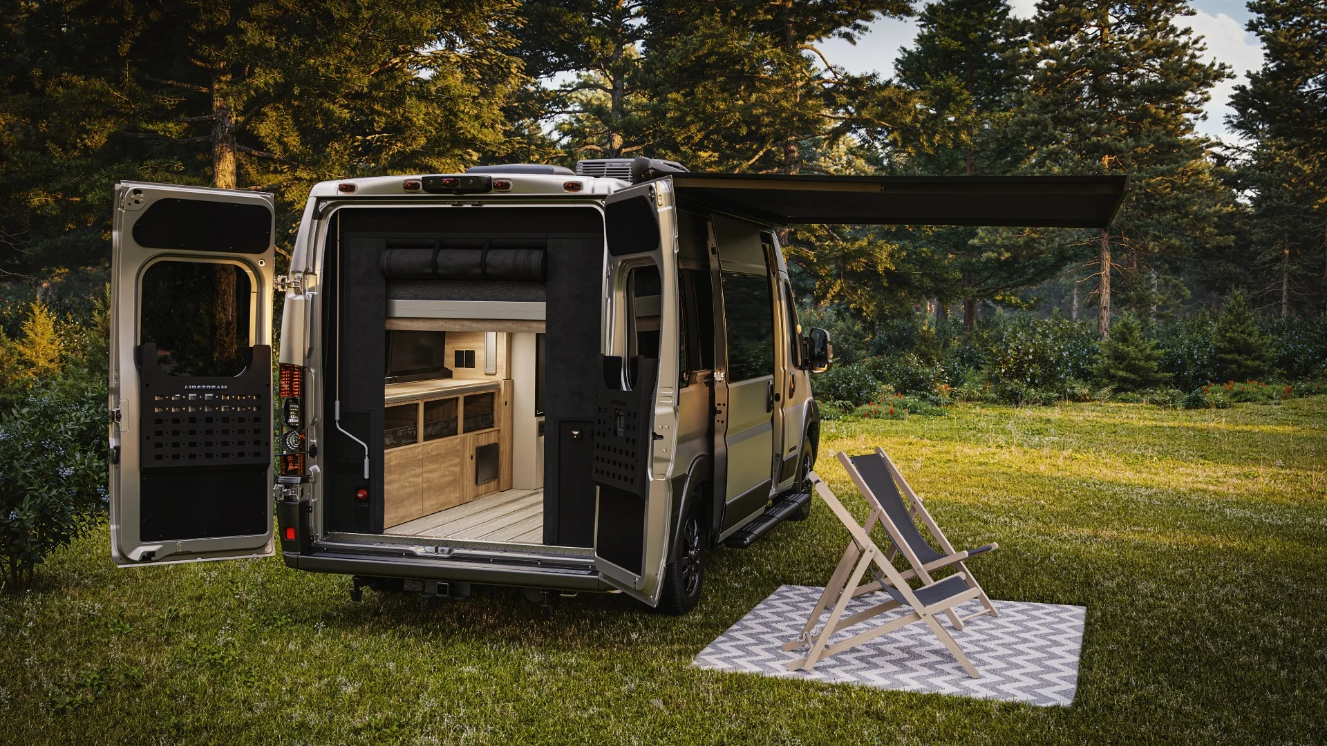 Camper van with open doors showing interior, parked in a forest. Two chairs on a patterned rug are set up outside under an awning.