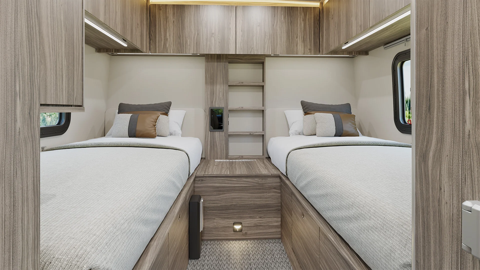 Modern RV interior with two twin beds, matching wood cabinets, and overhead storage, featuring neutral tones and ample natural light through windows.