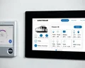 Two smart control panels on a wall: one displaying a temperature of 71°F, the other showing Airstream RV system details like battery and water levels.