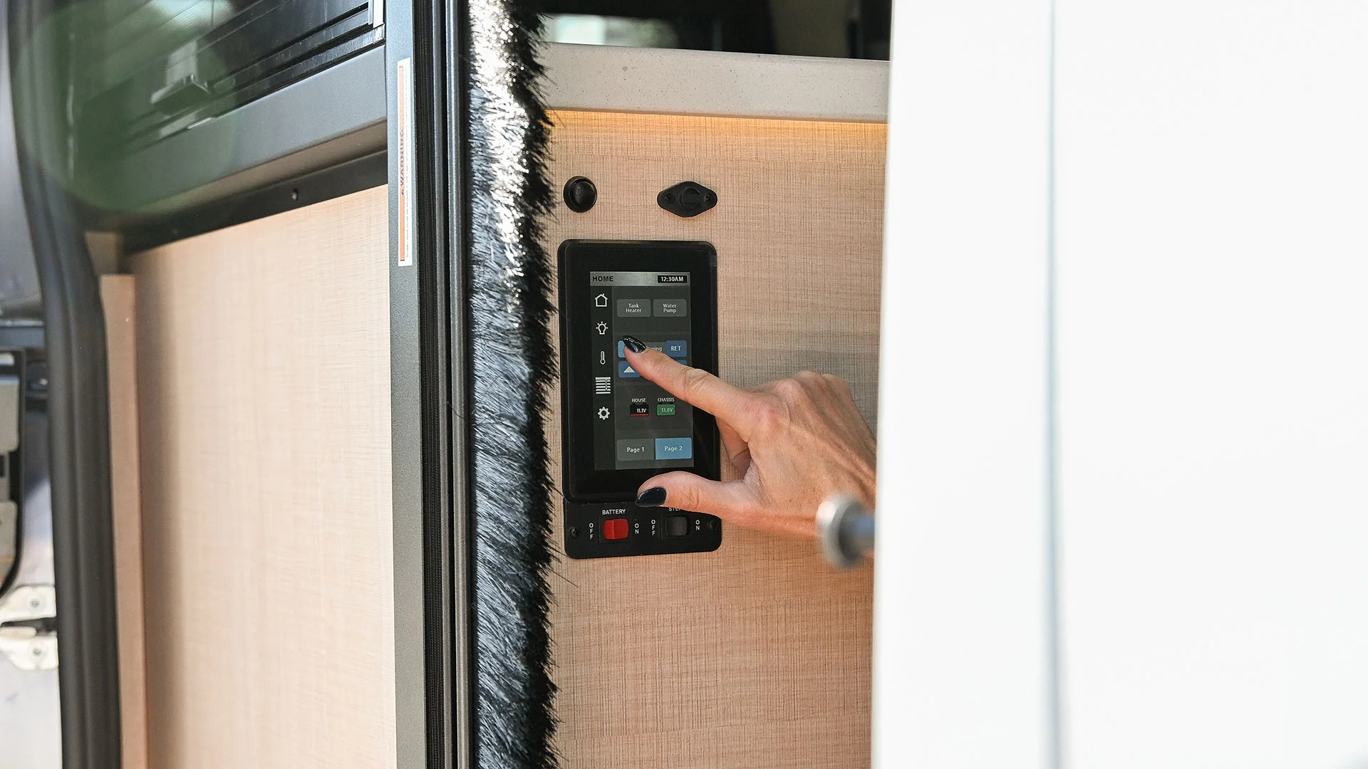 Person using a touchscreen control panel inside a vehicle, with a sleek, modern interface and wooden interior wall.