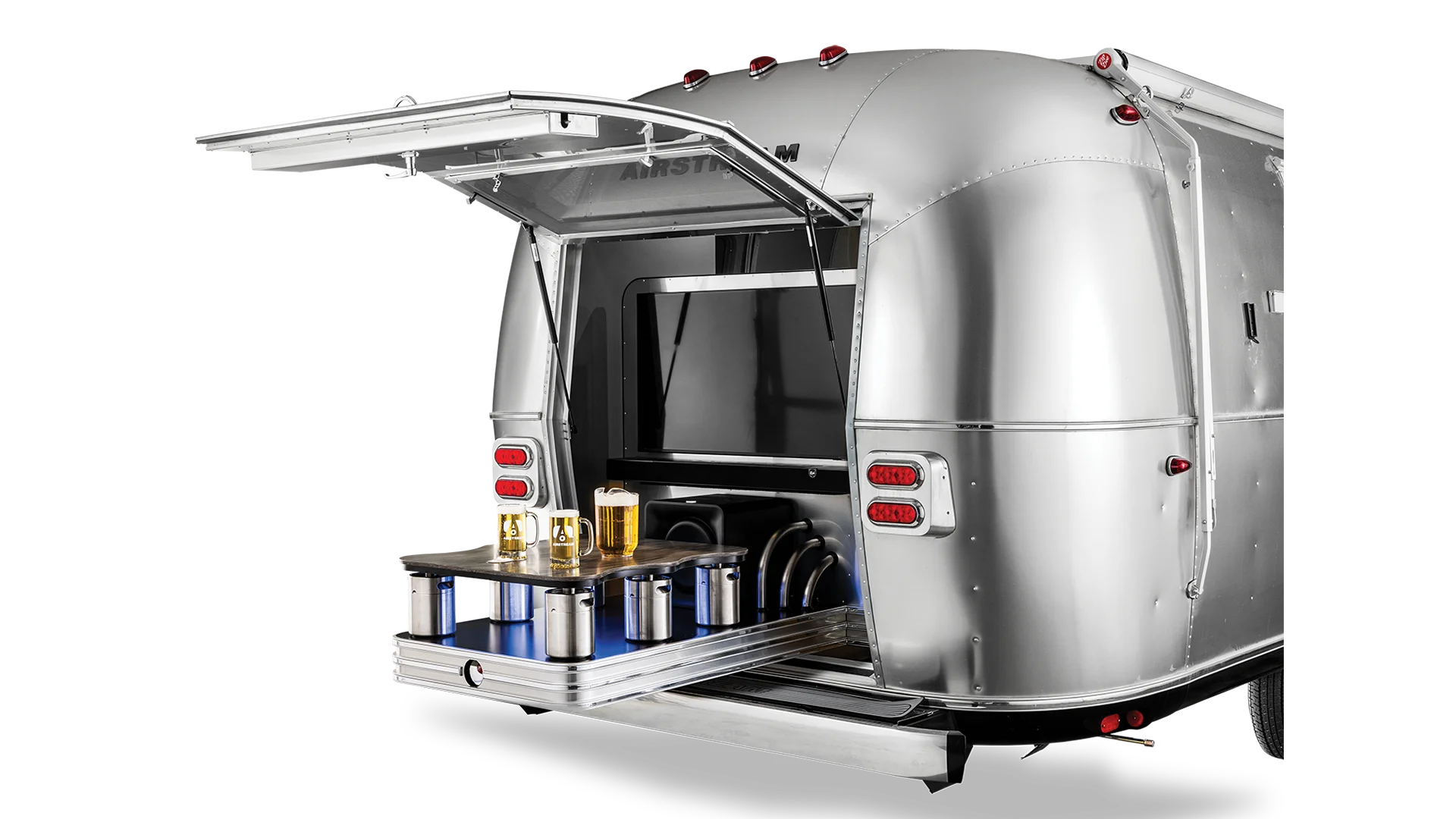 Silver Airstream trailer with an open hatch revealing a bar setup with drinks and containers on a sliding shelf.