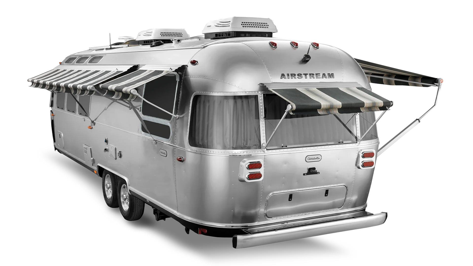 A silver Airstream trailer with striped awnings extended over its windows and door, showcasing a classic, streamlined design.