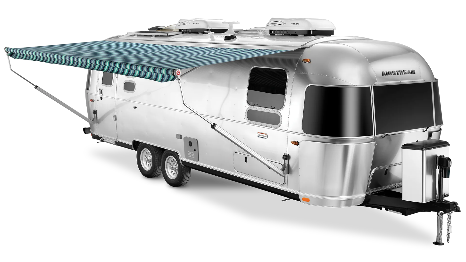 Silver Airstream travel trailer with a blue striped awning extended. It features a sleek design with rounded edges and multiple windows.