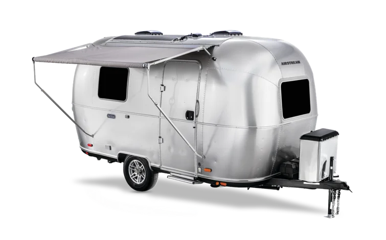 Silver Airstream travel trailer with extended awning, black windows, and a front storage compartment on a black background.