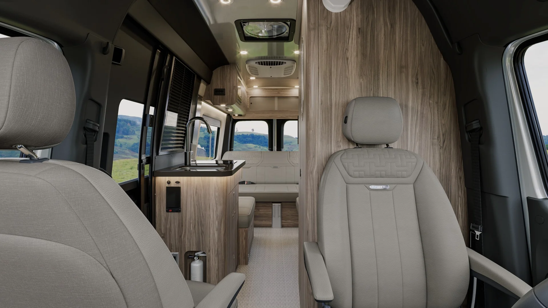 Interior of a modern camper van with beige seating, wood paneling, a small kitchen area, and a scenic view through the windows.