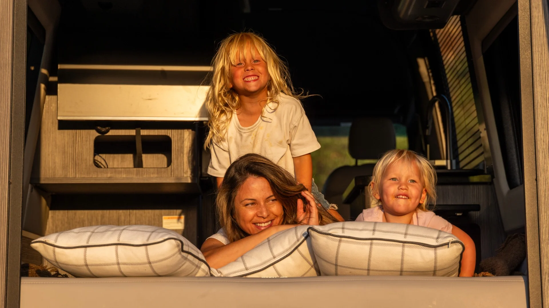Family laying on pillows on the bed of a Airstream camper van