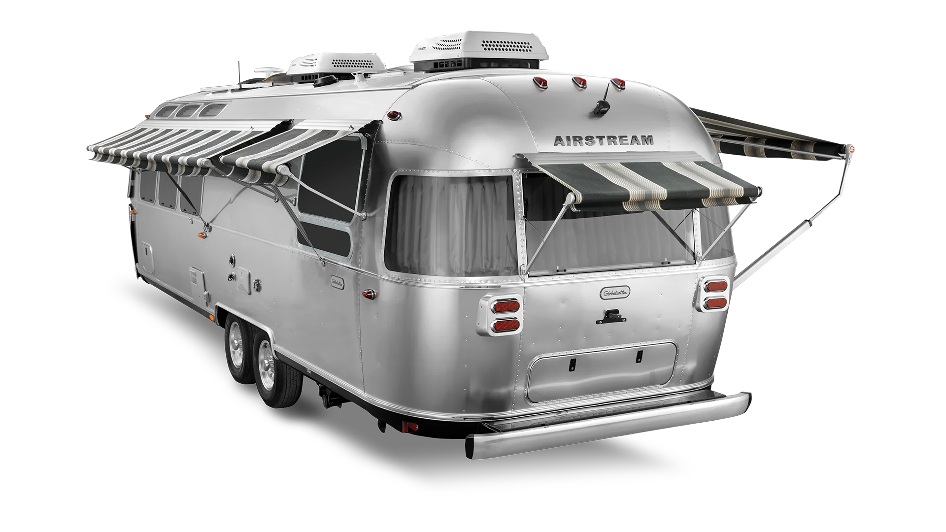 Silver Airstream trailer with striped awnings extended, showcasing wheels and rear lights against a white background.