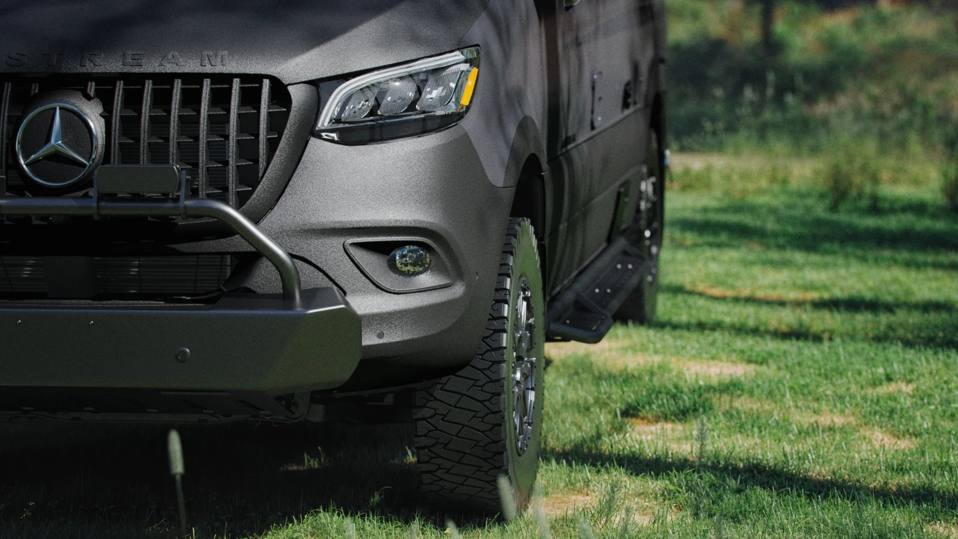 Close-up of a rugged black vehicle with large off-road tires parked on green grass.