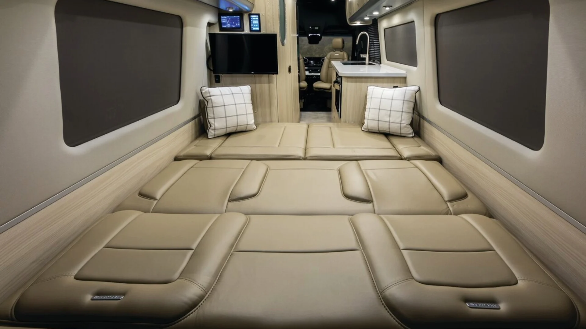 Camper Van bed converted to a bedded sleeping area with beige leather cushions