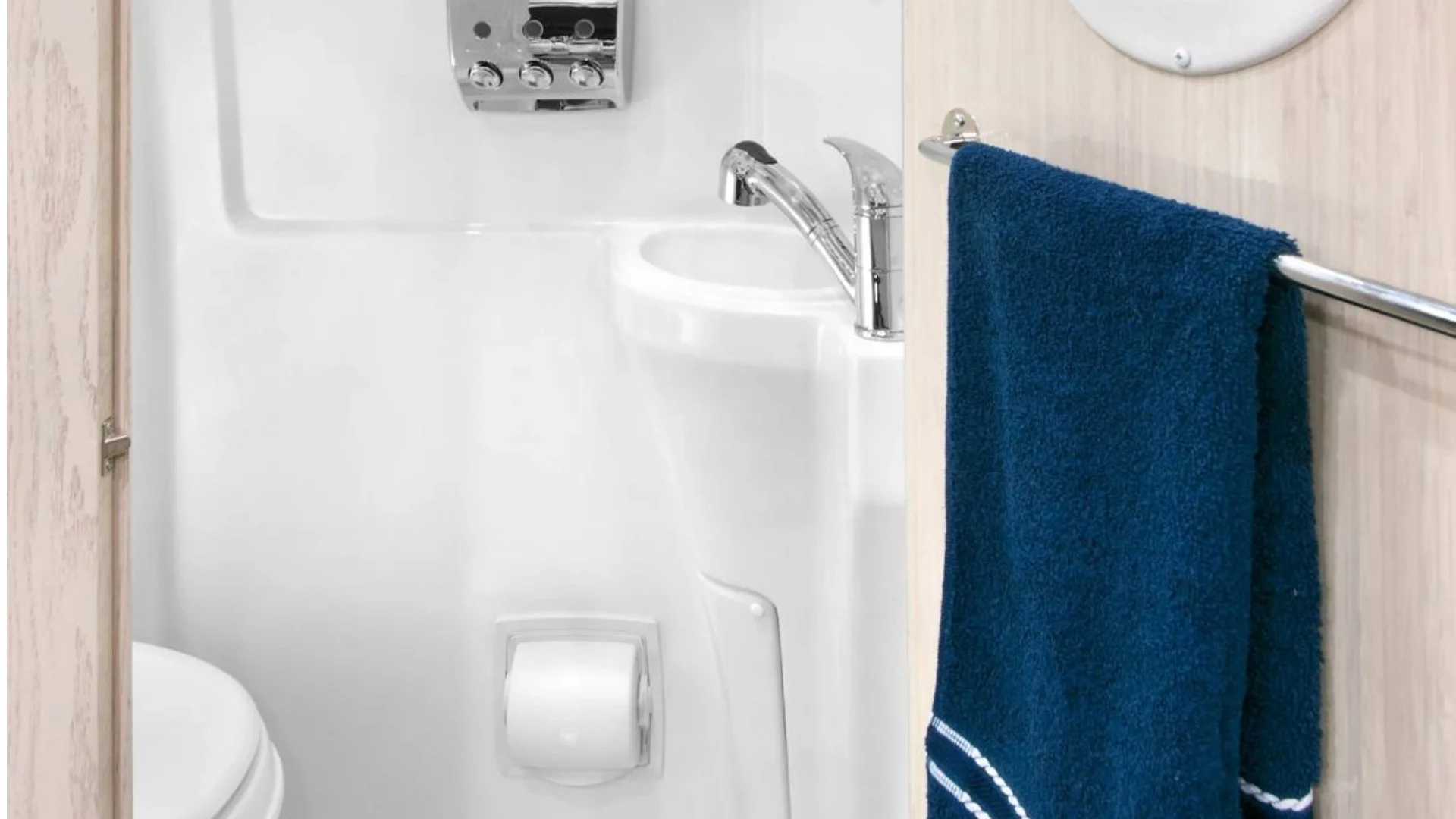 Small bathroom with a white sink, chrome faucet, toilet, toilet paper holder, and a blue towel on a rack.