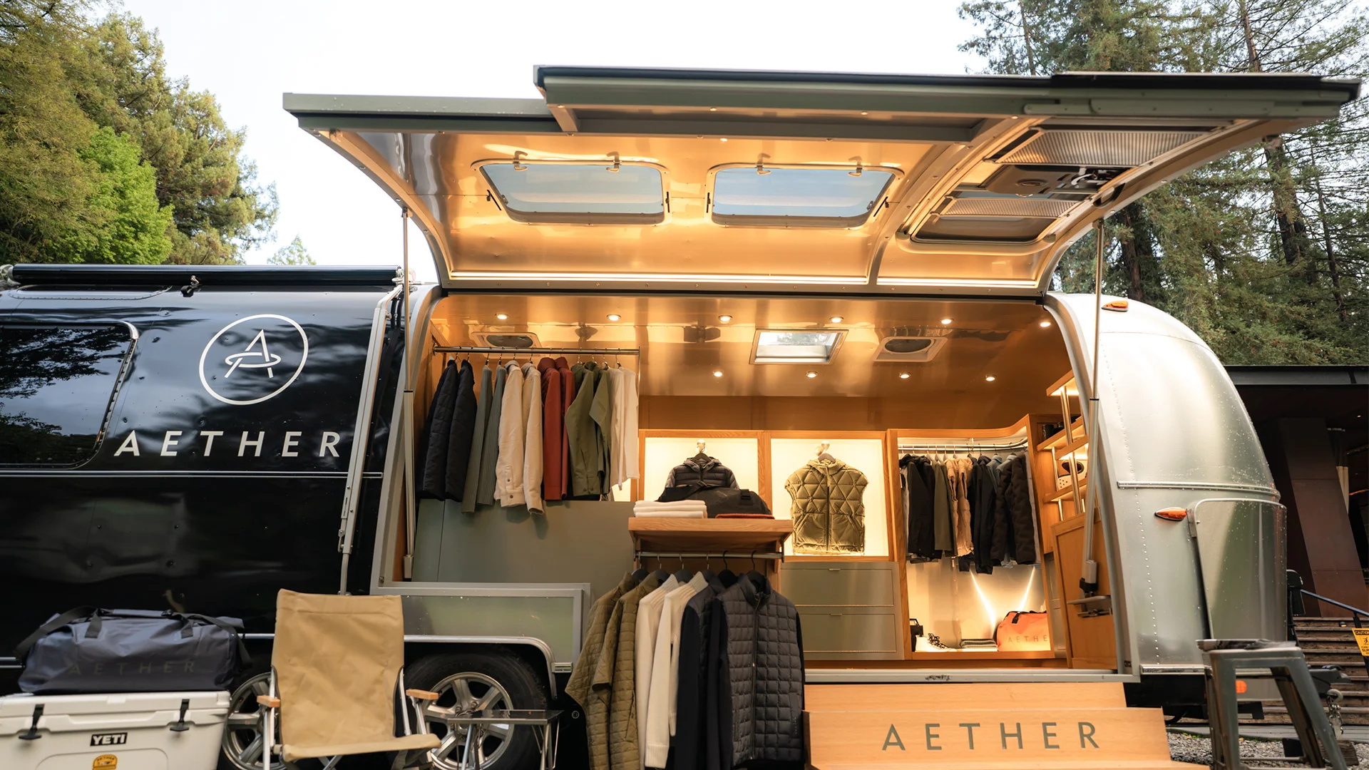Vintage trailer turned into a mobile clothing store, with jackets and coats on display inside.