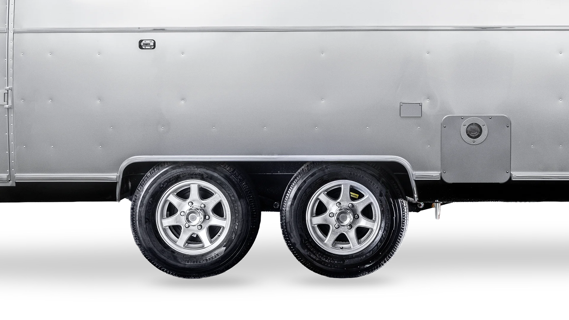 Silver trailer side with two chrome wheels and visible paneling.