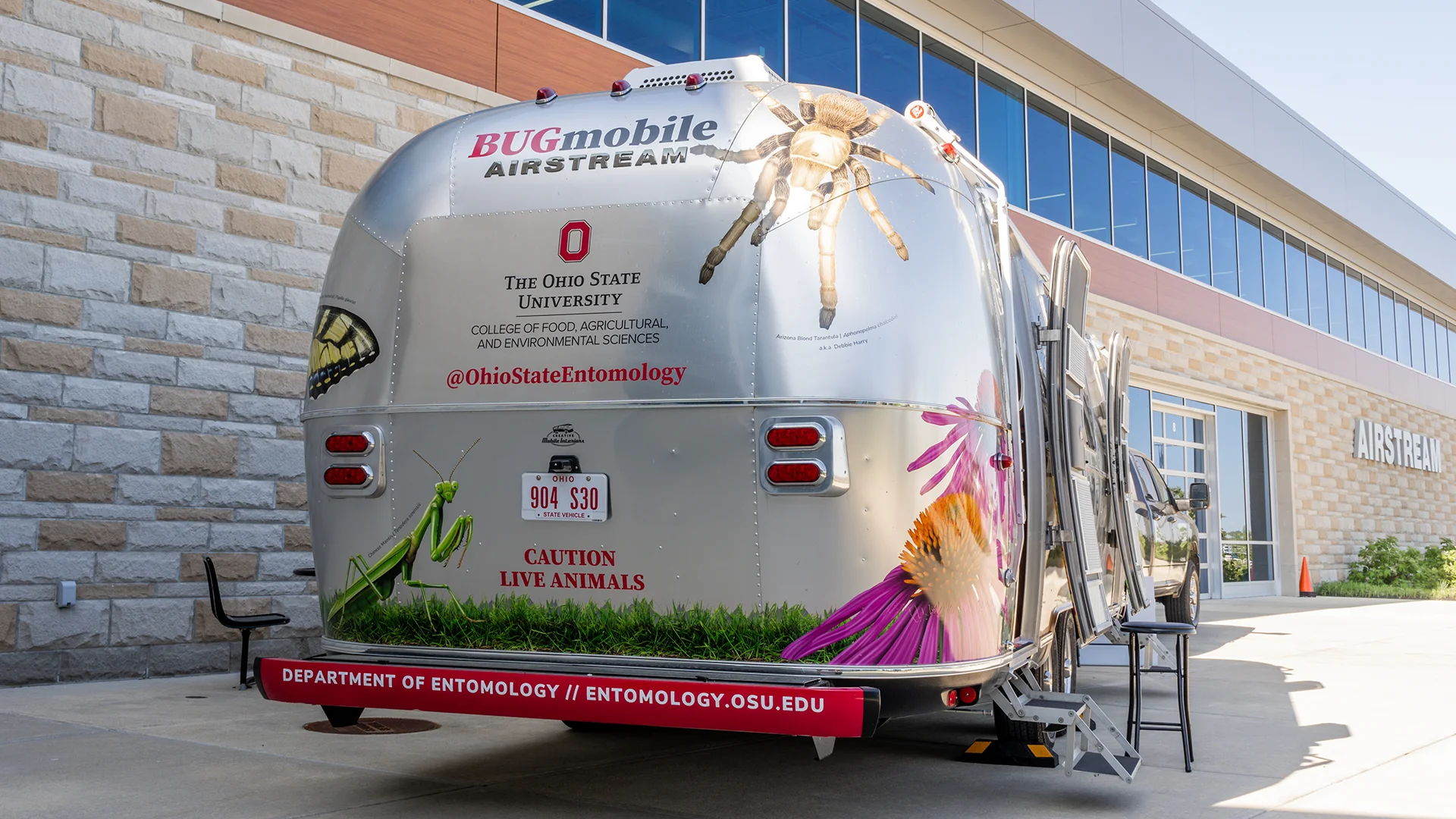 Silver Airstream trailer labeled "BUGmobile" features insect images, promoting Ohio State University's entomology department.