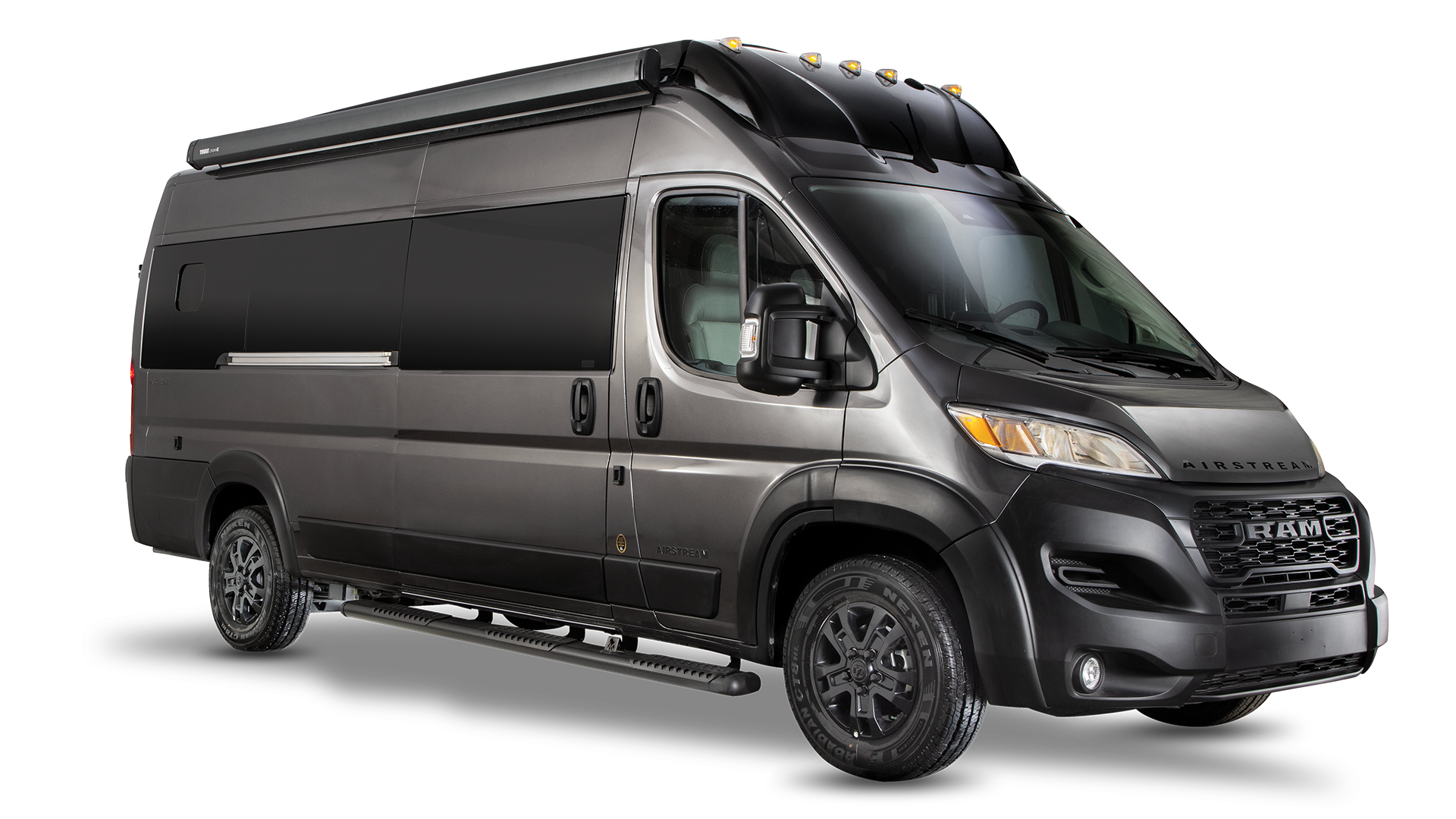 A gray camper van with tinted windows, side steps, black wheels, and a roof-mounted awning, viewed from the front and left side.