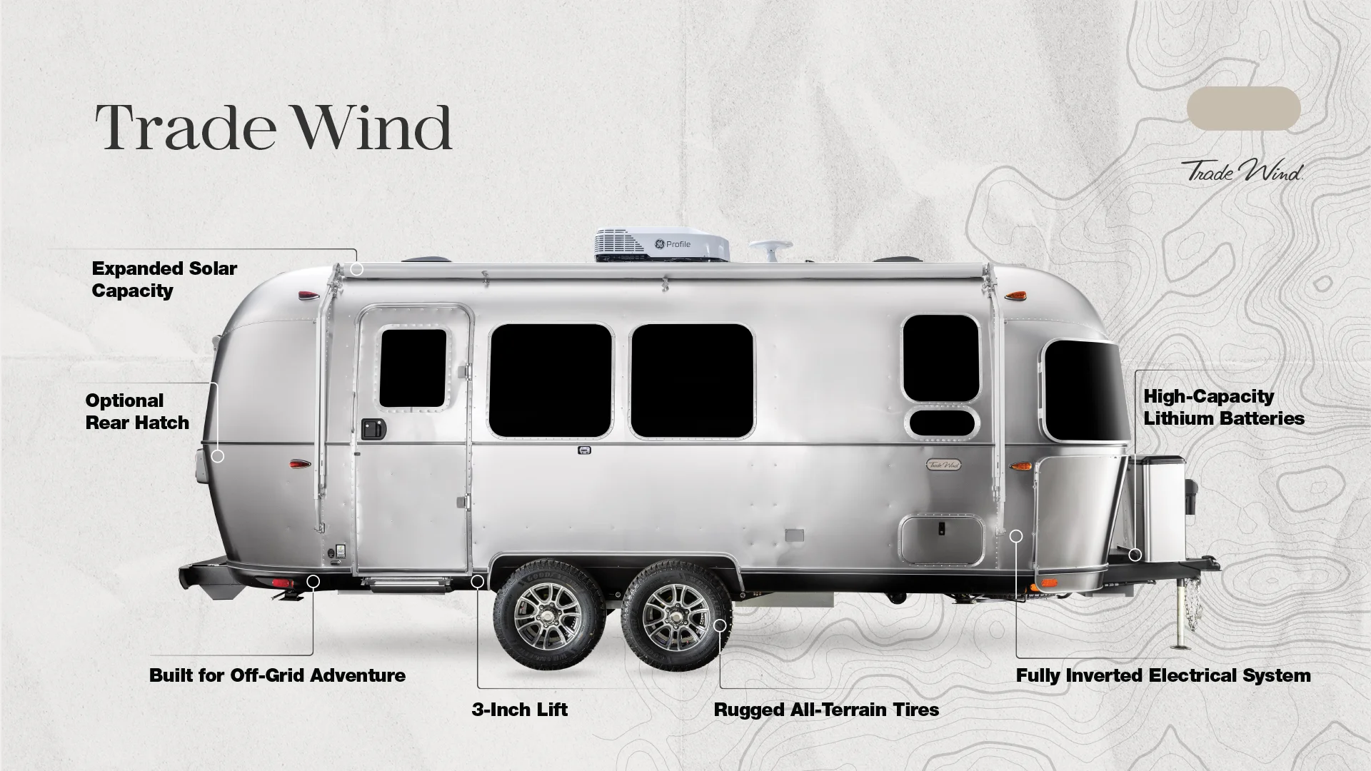 Silver travel trailer labeled "Trade Wind" features expanded solar capacity, off-grid build, 3-inch lift, rugged tires, and high-capacity batteries.