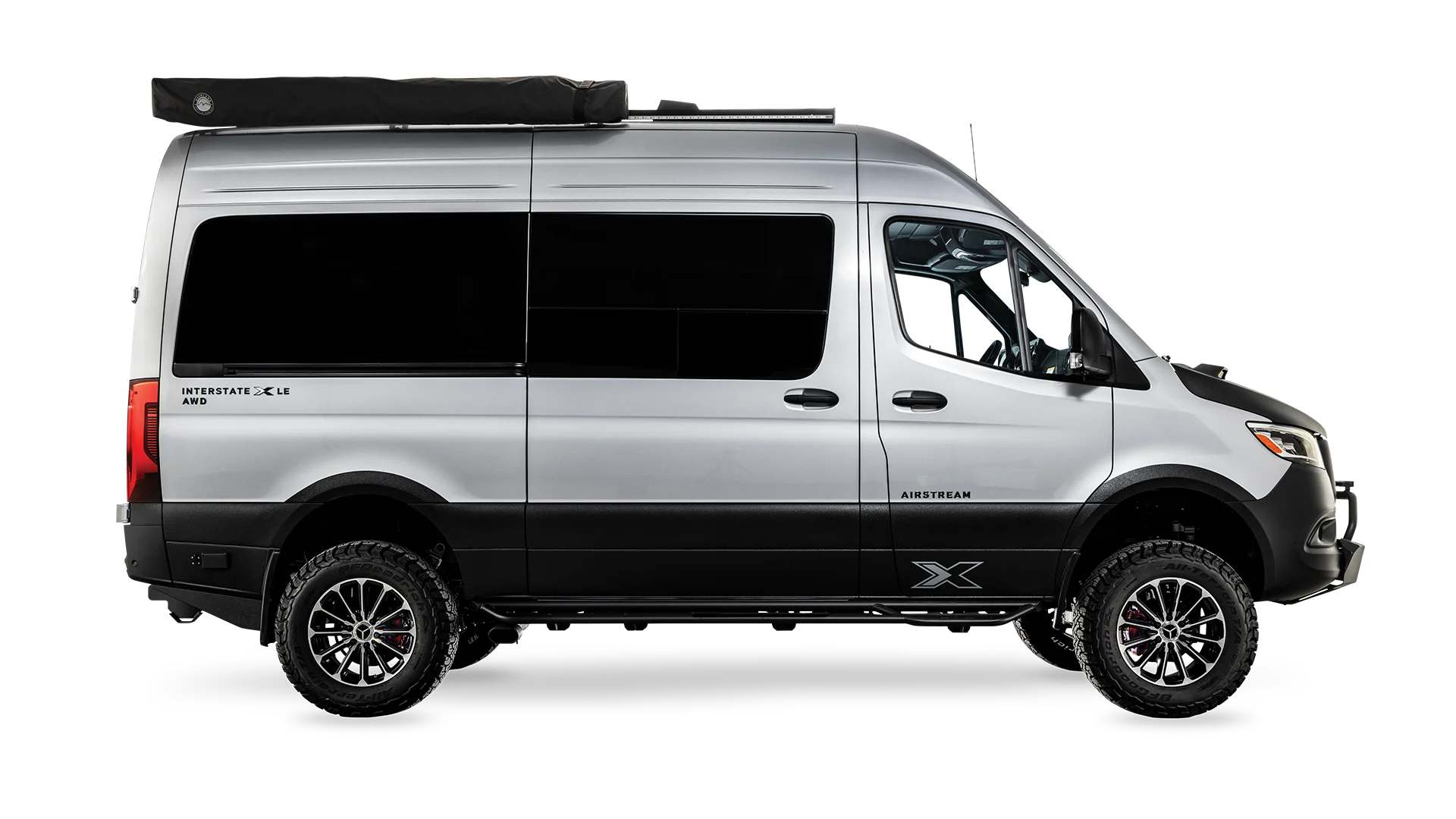 Silver van with a black roof rack and off-road tires, shown in a side view on a white background.